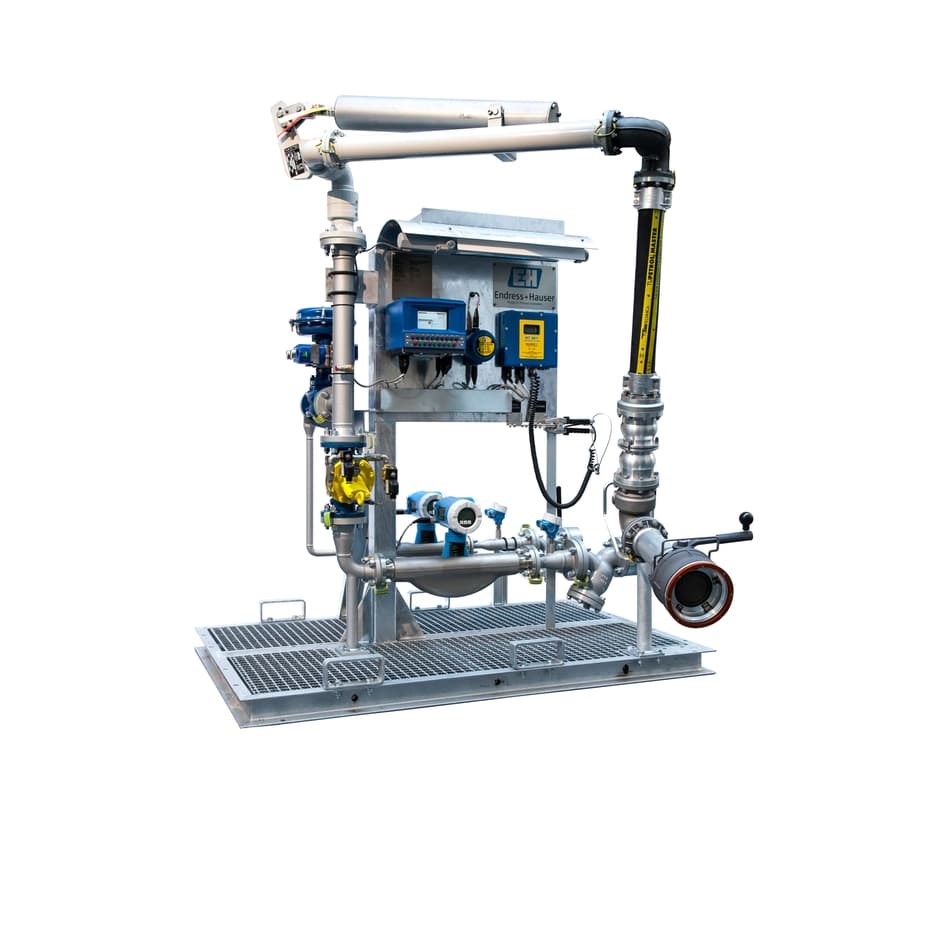 Industrial fluid metering skid with complex piping, electronic control panels, and a flexible loading arm.